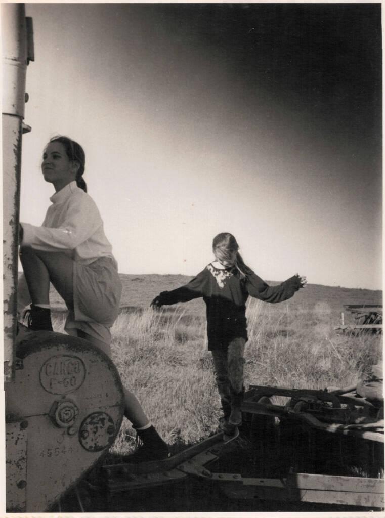 Two girls playing at the vineyard on a tractor.