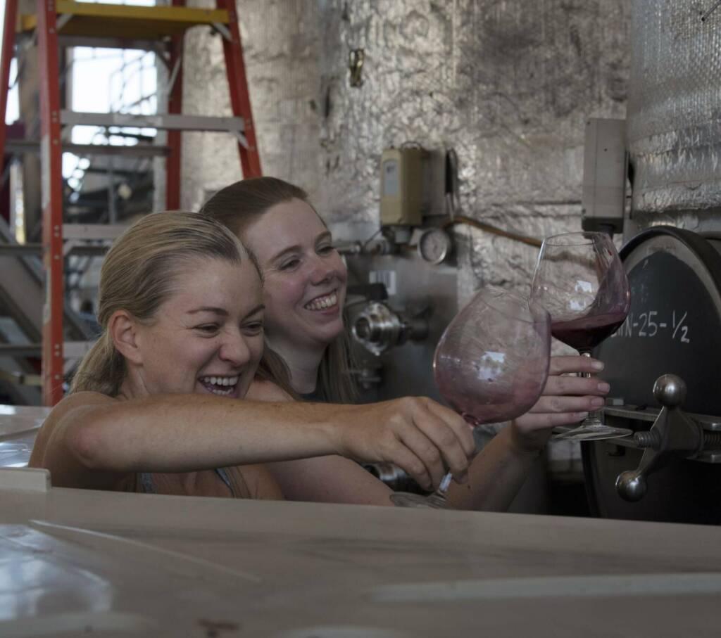 Jasmine Hirsch and Melissa Beck tasting wine out of a fermenter.